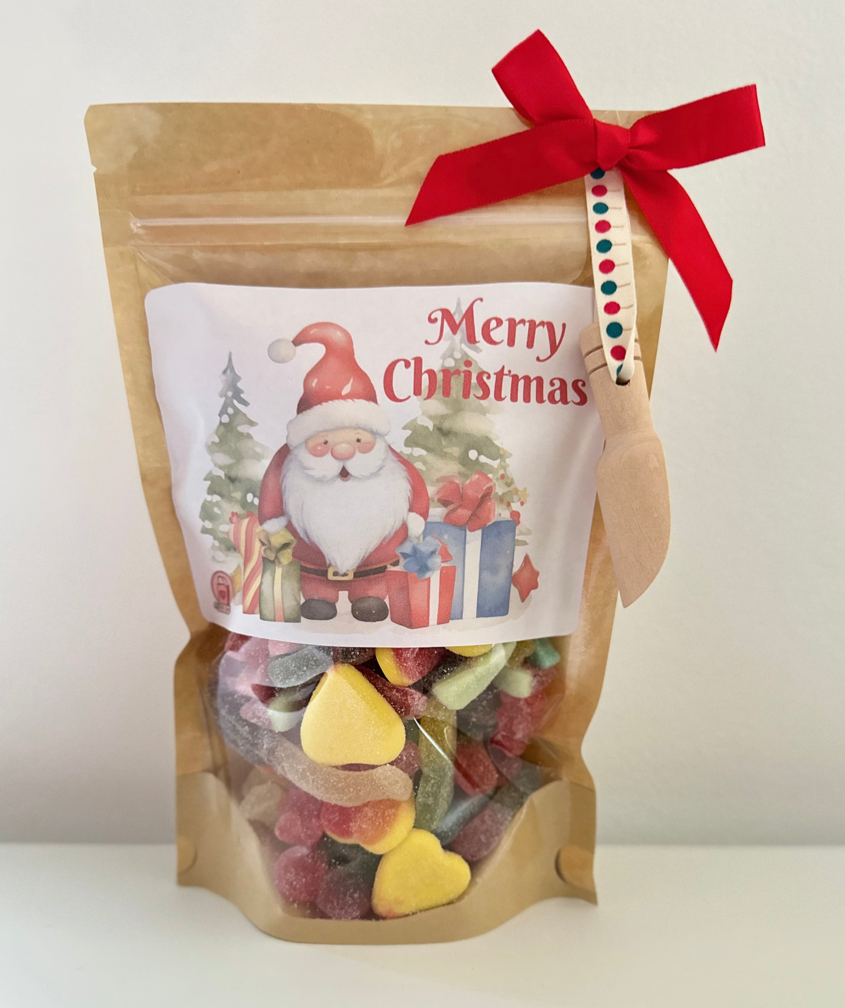 Bag of colorful candies with a Christmas-themed label and red ribbon on a white background