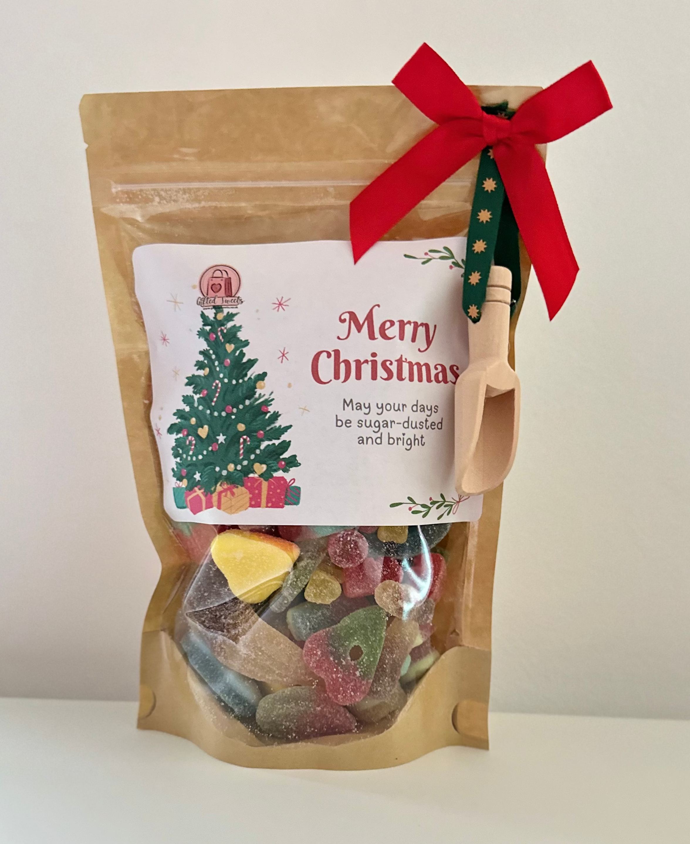 Kraft paper bag with Christmas-themed label and candy, tied with a red ribbon on a white background.